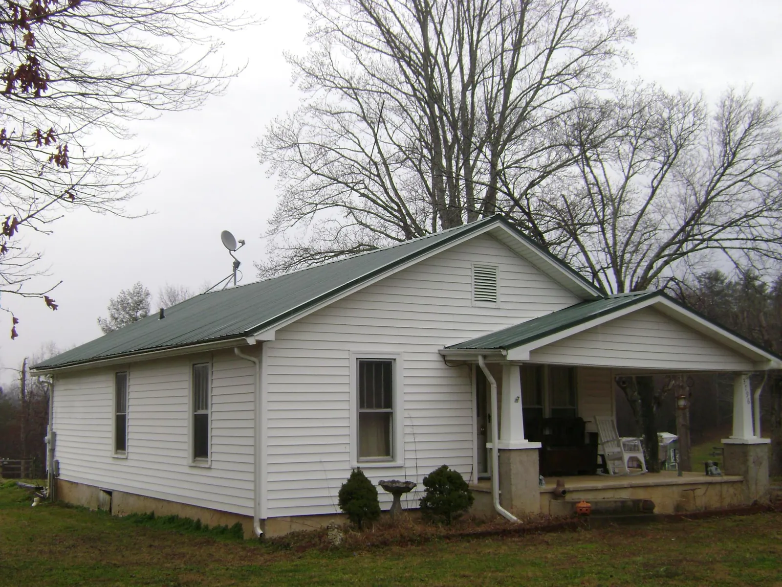 Green metal roof on a white bungalow with a side porch in Peoria