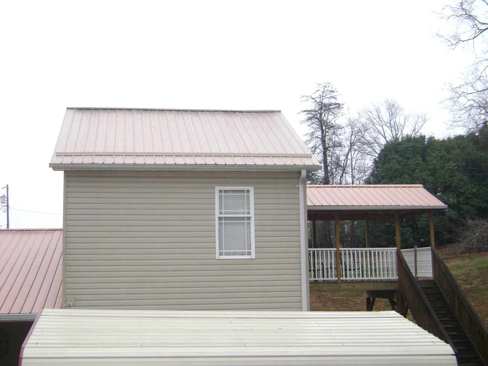 Tan metal roofs on a two story addition and attached porch, from a Roof Replacement job in Peoria