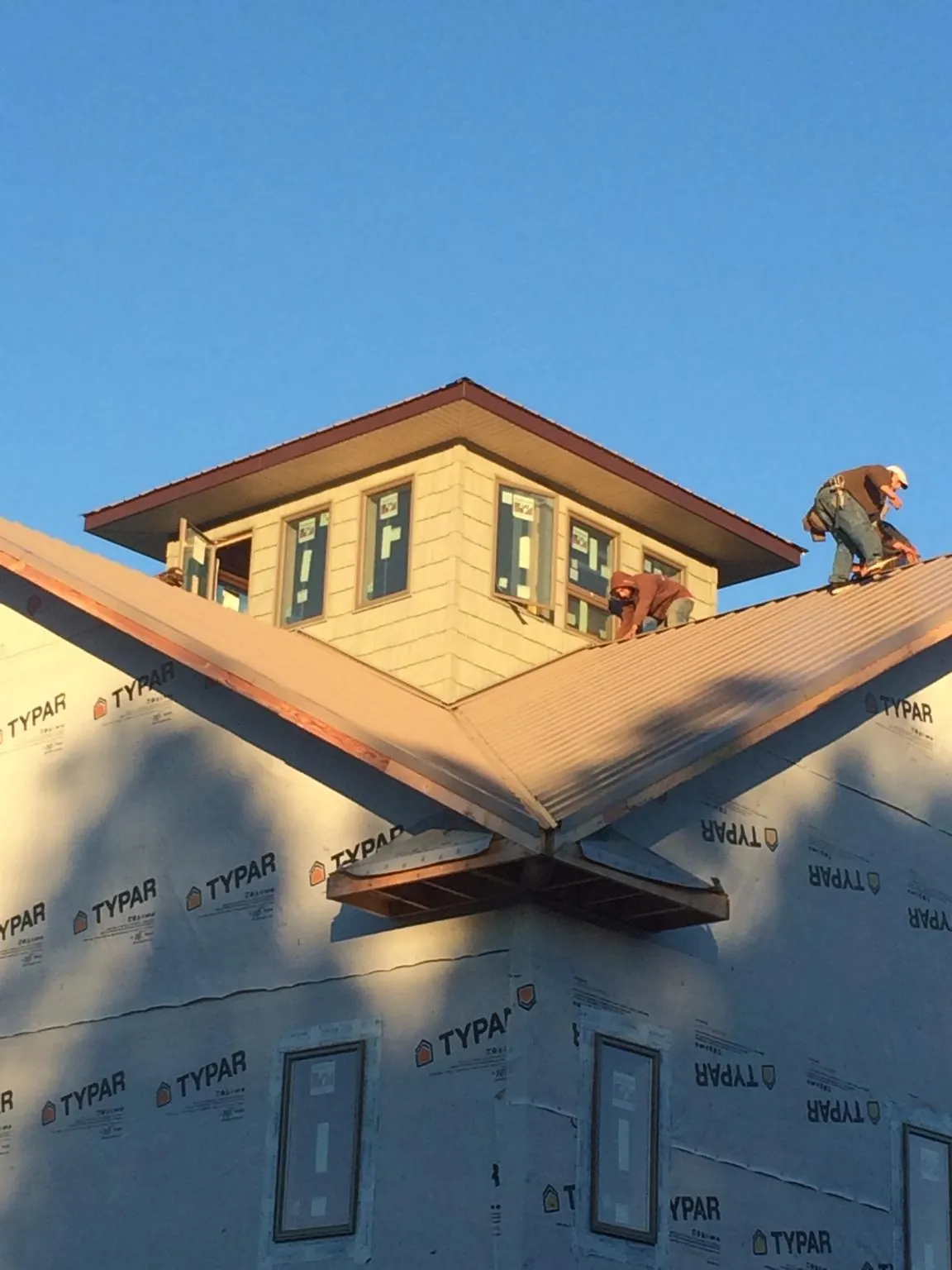 Roofers working around a rooftop cupola on a new metal roof at sunset — Roof Waterproofing in Peoria by Roofing Brothers